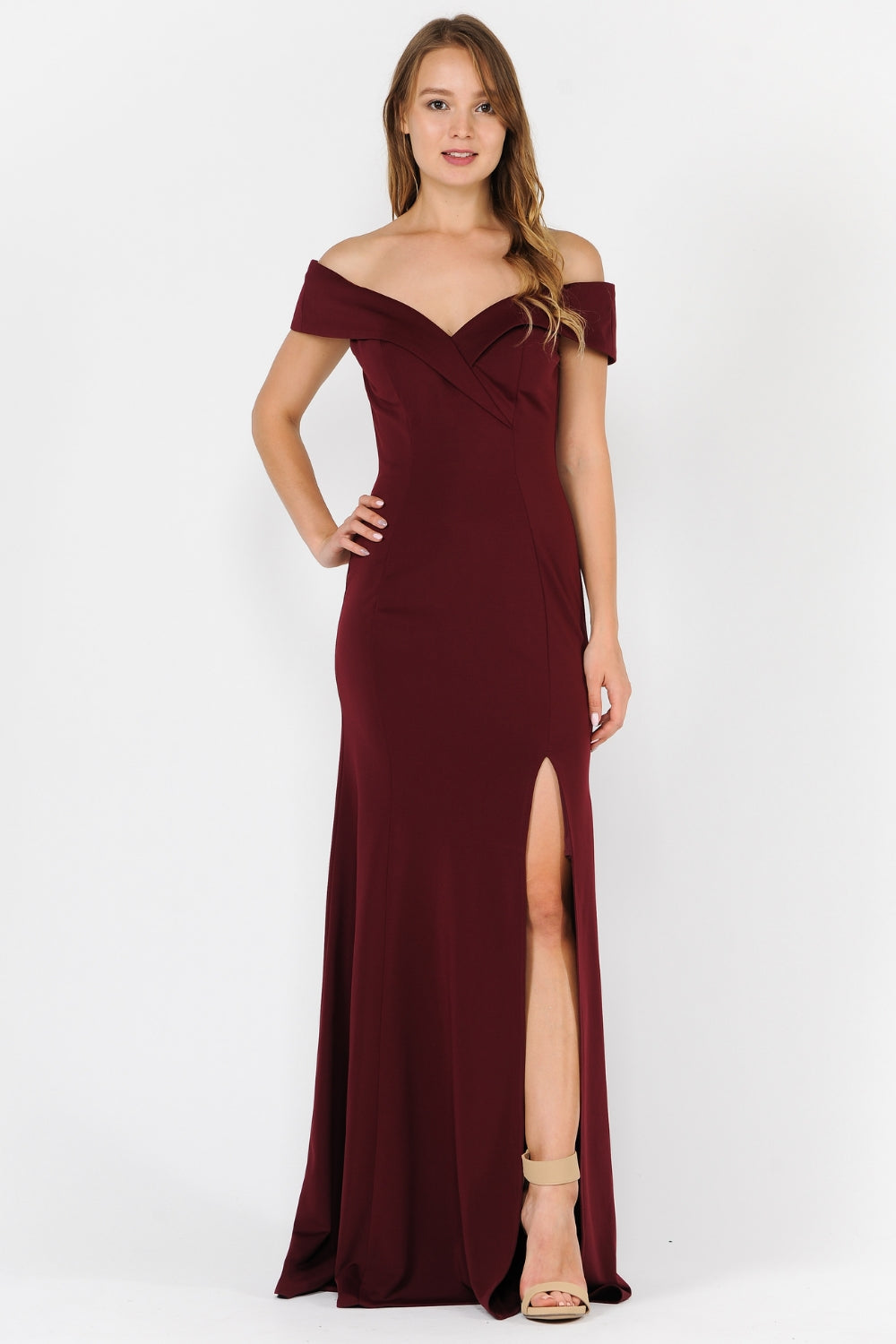 A woman wears the Classic Off-the-Shoulder Formal Prom Dress 8258 in burgundy, featuring a front slit, paired with beige high-heeled sandals against a plain white background.